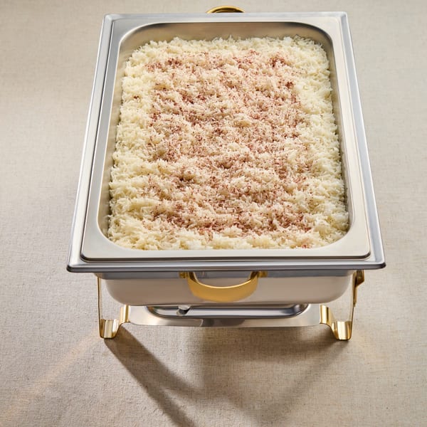 A large catering pan filled with white rice, lightly sprinkled with a reddish-brown spice.