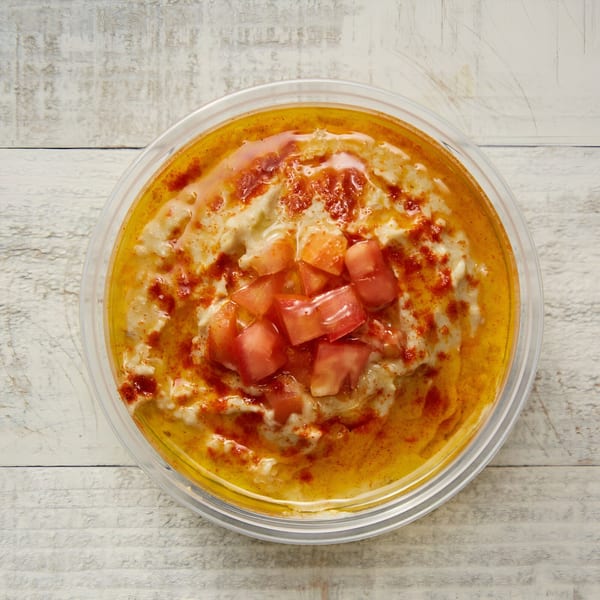 Manakish Oven & Grill's creamy hummus topped with diced tomatoes, olive oil, and paprika.