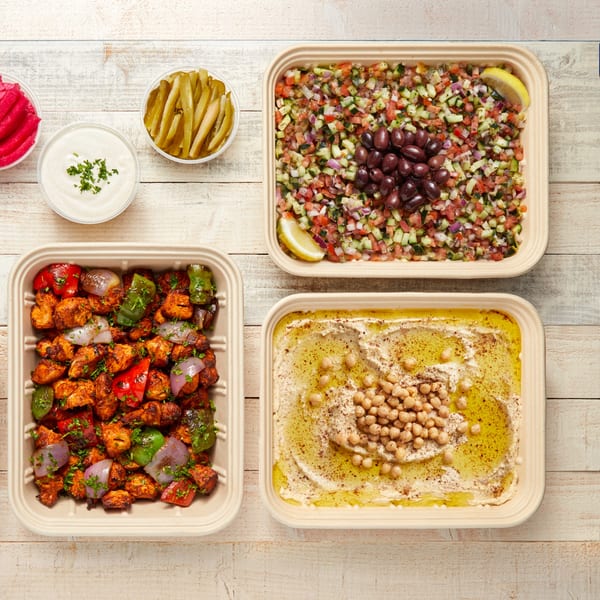Manakish Oven & Grill's Mediterranean feast: chicken shish tawook, hummus, salad, pickles, and garlic sauce.