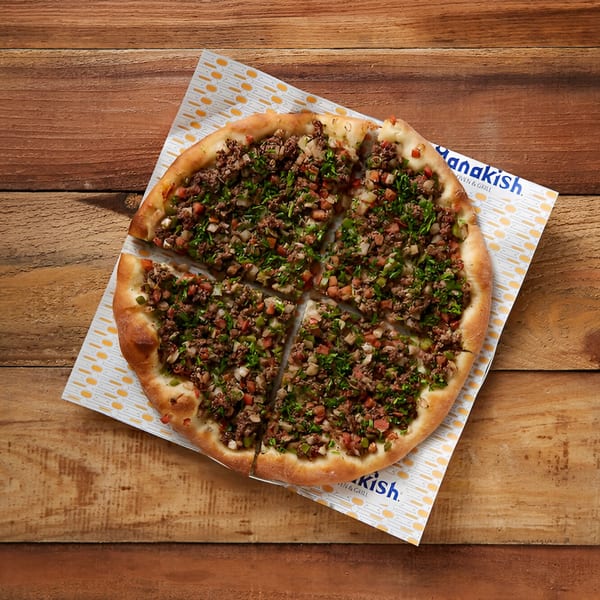 Manakish Oven & Grill's meat manakish, a round flatbread topped with minced meat, herbs, and vegetables.